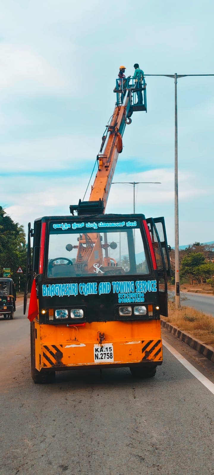 ಮ್ಯಾನ್ ಲಿಫ್ಟ್‌ನಿಂದ ಬೀದಿದೀಪ ನಿರ್ವಹಣೆ — Crane-mounted personnel basket for streetlight maintenance near Bhatkal